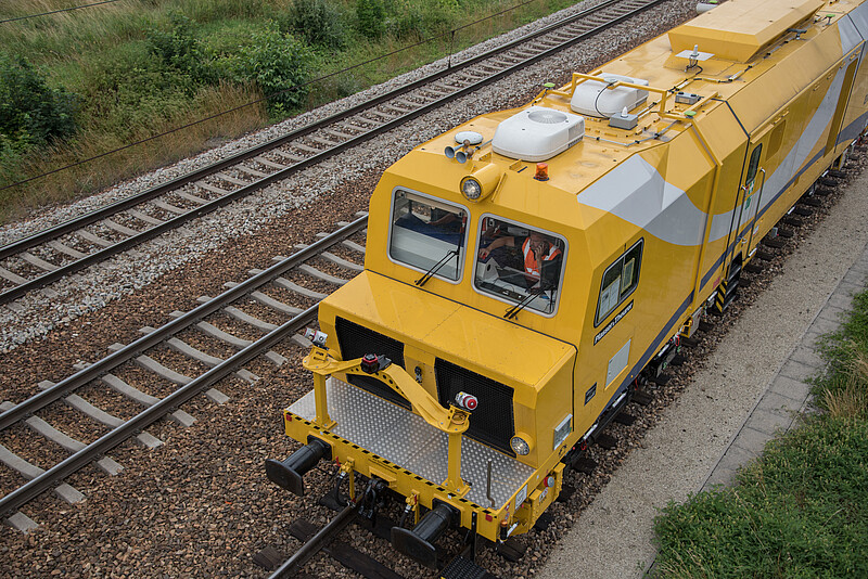 Yellow measuring vehicle in the track, seen from above at an angle.