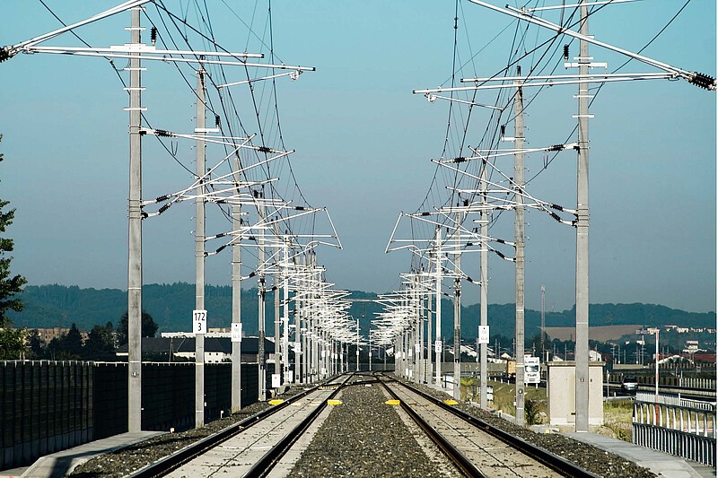 High-speed overhead line with return cable and reinforcement line over two tracks and in front of a blue sky